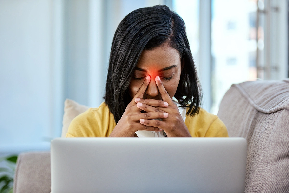 A woman struggling with a persistent blocked nose while working on her laptop